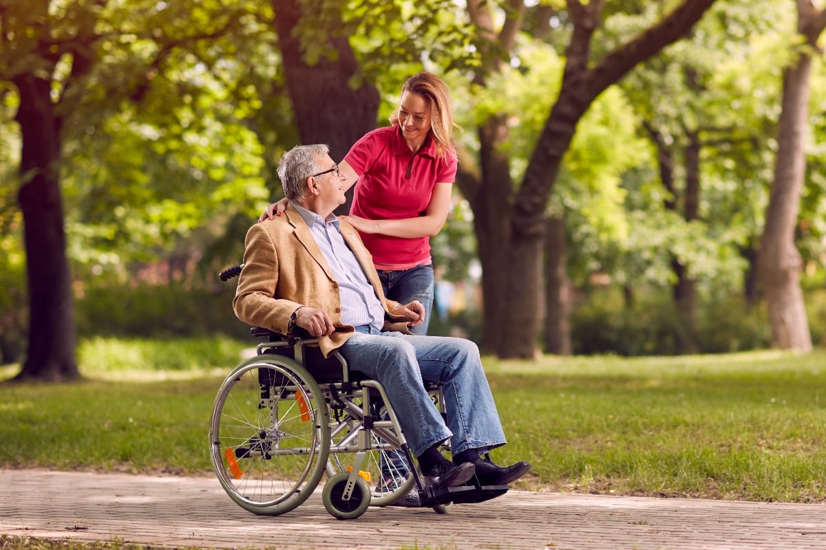 senior man in wheelchair in the park with daughter.