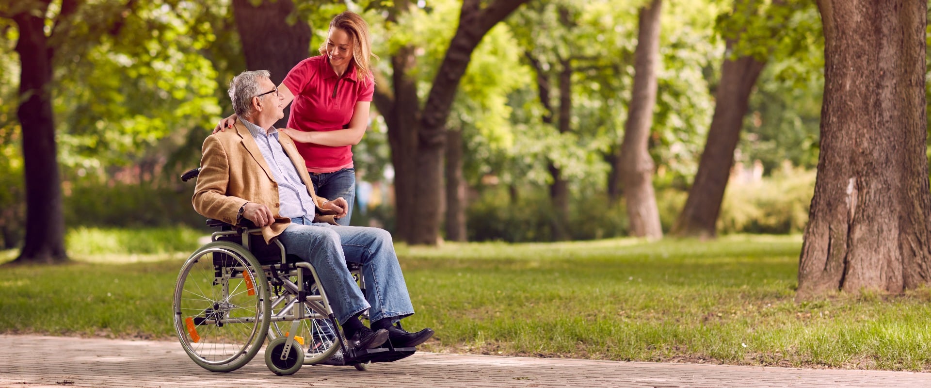 senior man in wheelchair in the park with daughter.